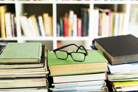 A Pair Of Spectacles Lie On Top Of A Pile Of Books In A Library - W2