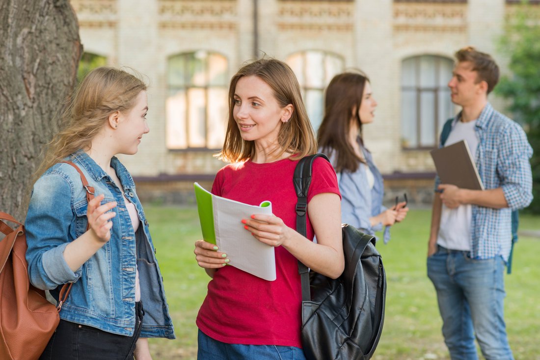 Studenci rozmawiają przed budynkiem uczelni