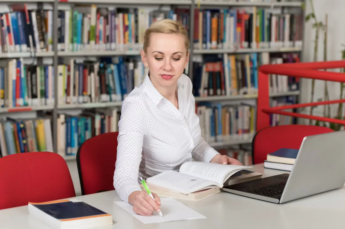 Studentka prawa z ksiazkami w bibliotece uniwersyteckiej
