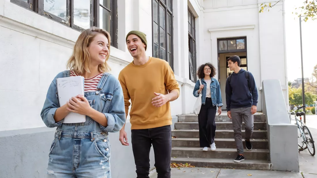 Czworo studentów rozmawia, wychodząc z budynku uczelni