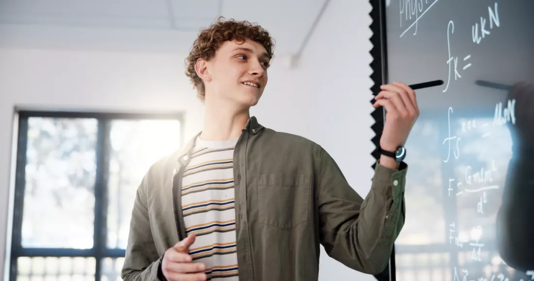 Student zapisuje wzory na tablicy podczas zajęć